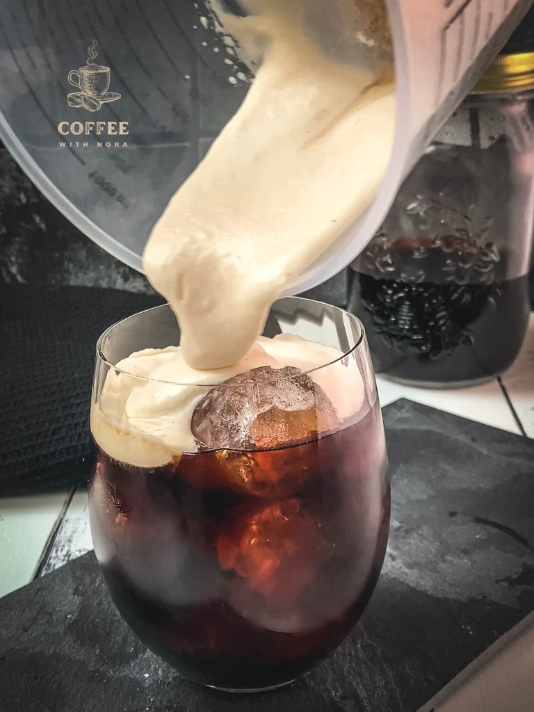 Adding the homemade vanilla sweet cream to the cold brew.