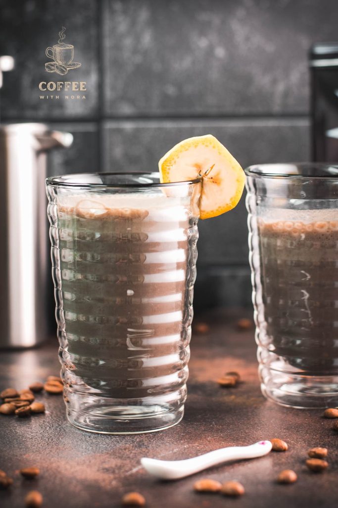 Two glasses filled with delicious, nutritious banana milk coffee. Garnished with a slice of banana. Perfect to start the day or as a pre-workout snack!