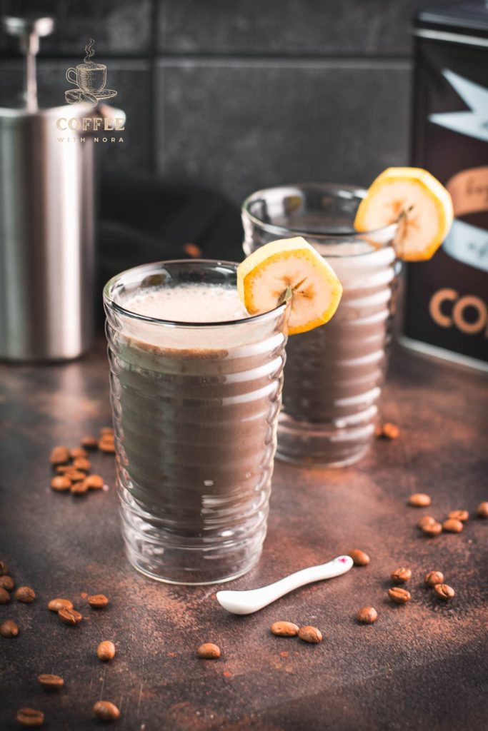 Two glasses filled with delicious, nutritious banana milk coffee. Garnished with a slice of banana. Perfect to start the day or as a pre-workout snack!