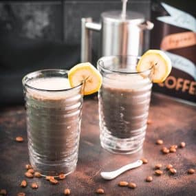 Two glasses filled with delicious, nutritious banana milk coffee. Garnished with a slice of banana. Perfect to start the day or as a pre-workout snack!