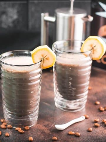 Two glasses filled with delicious, nutritious banana milk coffee. Garnished with a slice of banana. Perfect to start the day or as a pre-workout snack!