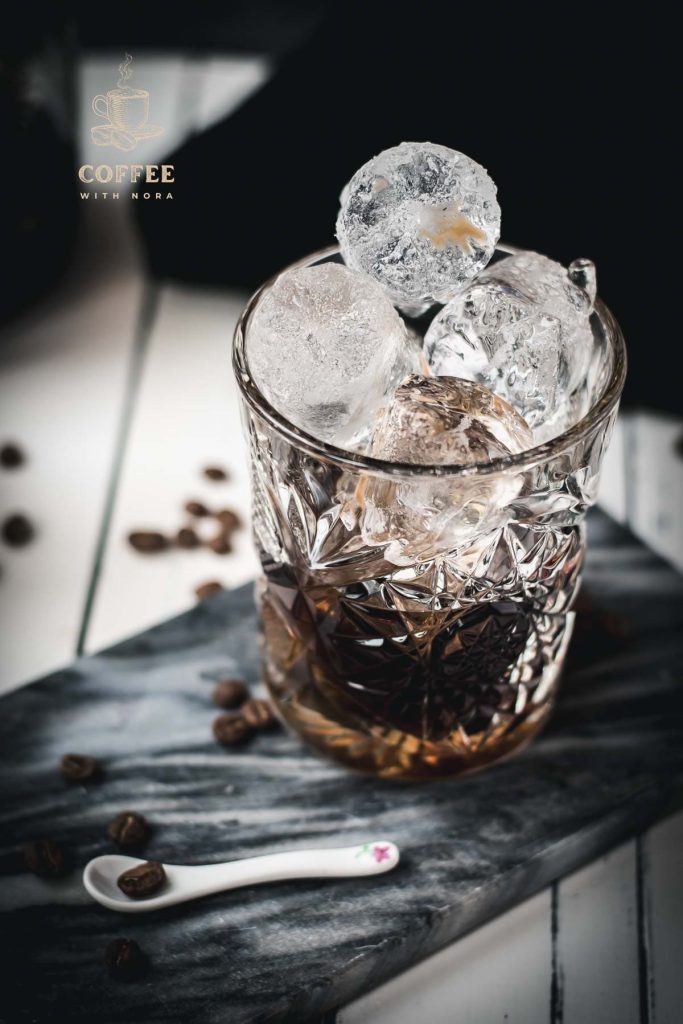 Gorgeous cold brew black Russian served in a rocks glass and placed on a marbled plate.