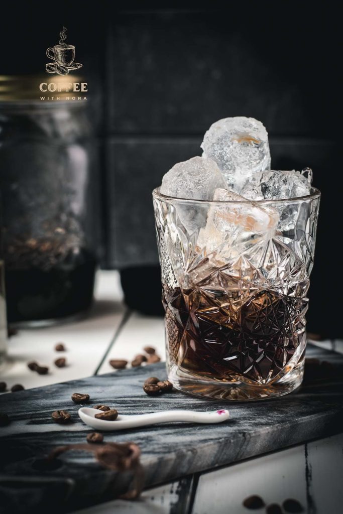 Gorgeous cold brew black Russian served in a rocks glass and placed on a marbled plate.