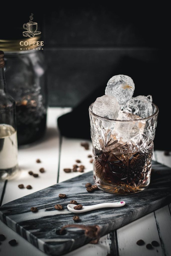 Gorgeous cold brew black Russian served in a rocks glass and placed on a marbled plate.