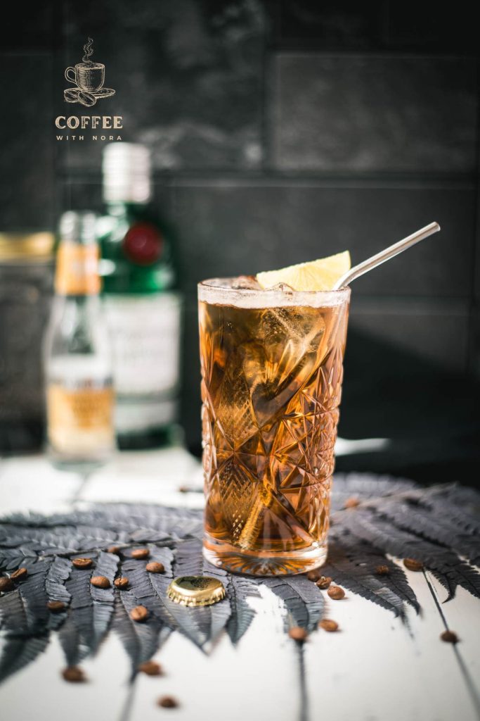 Gorgeous highball glass filled with cold brew gin and tonic. Garnished with a lime slice and served with a metal straw.