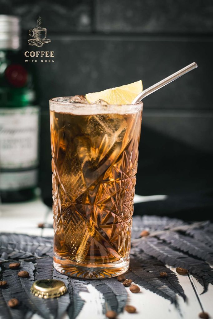 Gorgeous highball glass filled with cold brew gin and tonic. Garnished with a lime slice and served with a metal straw.