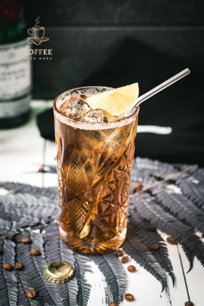 Gorgeous highball glass filled with cold brew gin and tonic. Garnished with a lime slice and served with a metal straw.