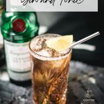 Gorgeous highball glass filled with cold brew gin and tonic. Garnished with a lime slice and served with a metal straw.