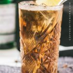 Gorgeous highball glass filled with cold brew gin and tonic. Garnished with a lime slice and served with a metal straw.