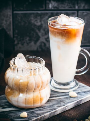 Two gorgeous glasses filled with delicious almond milk latte, placed on marbled plate