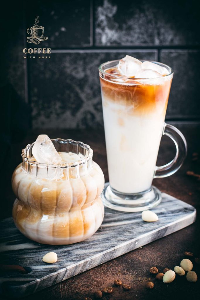 Two gorgeous glasses filled with delicious almond milk latte, placed on marbled plate