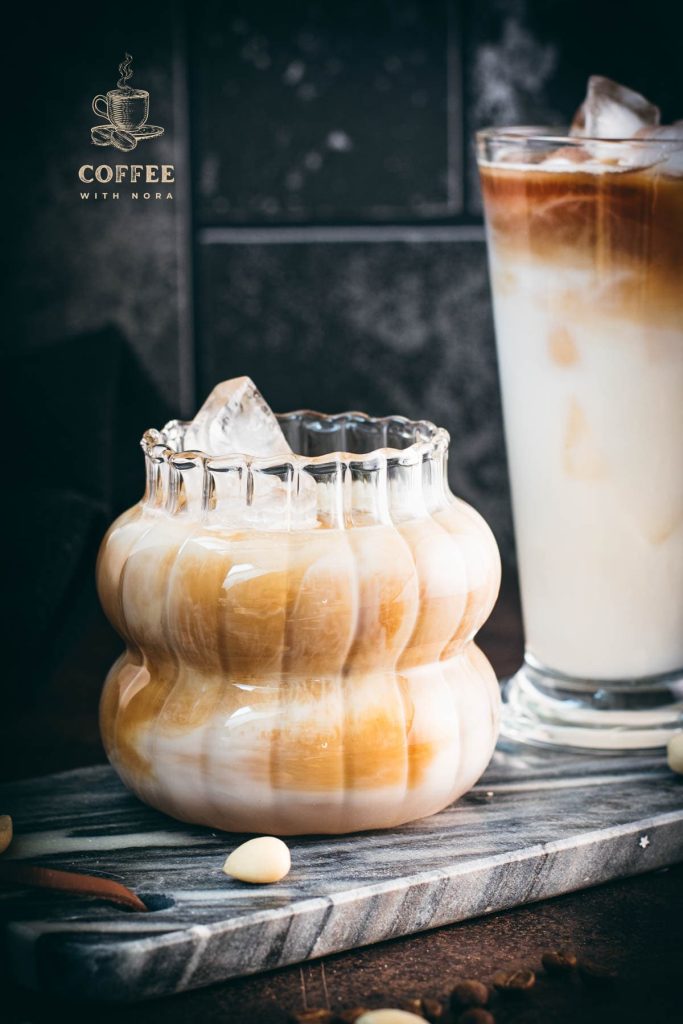 Two gorgeous glasses filled with delicious almond milk latte, placed on marbled plate