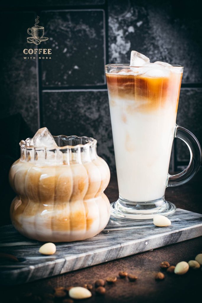 Two gorgeous glasses filled with delicious almond milk latte, placed on marbled plate