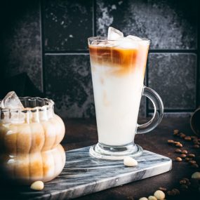 Two gorgeous glasses filled with delicious almond milk latte, placed on marbled plate