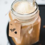 Mason jar filled with delicious iced coffee with vanilla ice cream, placed on a black plate.