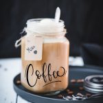 Mason jar filled with delicious iced coffee with vanilla ice cream, placed on a black plate.