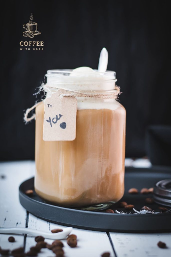 Mason jar filled with delicious iced coffee with vanilla ice cream, placed on a black plate.