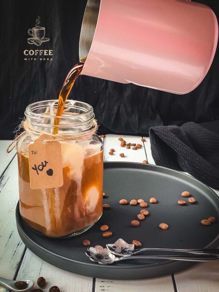 Pouring cold coffee into the mason jar filled with vanilla ice cream.