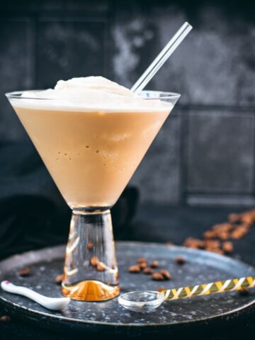 Gorgeous cocktail glass filled with a delicious homemade coffee slushy placed on a metal tray.