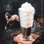 Beautiful tall glass filled with strong coffee and topped with whipped cream. Placed on brown coasters and pretty horse in the background. The Einspänner, a Viennese classic!