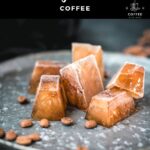 Frozen coffee cubes placed on metal plate next to coffee beans.