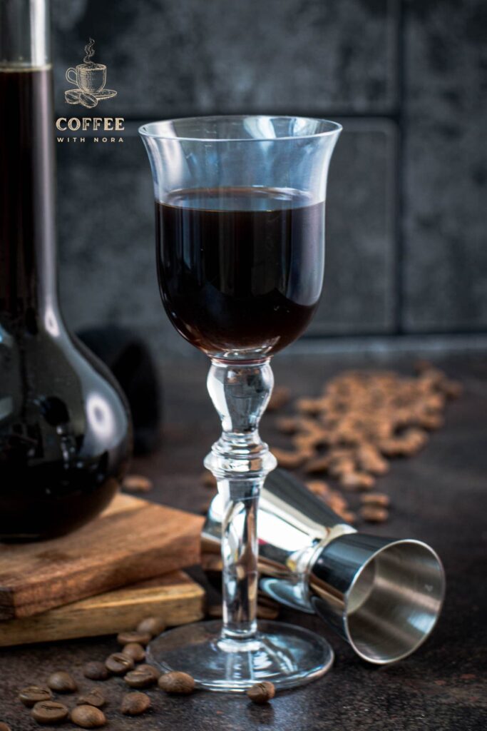 Gorgeous glass filled with homemade coffee liqueur, placed next to preserving jar and jigger.