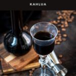 Gorgeous glass filled with homemade coffee liqueur, placed next to preserving jar and jigger.