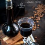 Gorgeous glass filled with homemade coffee liqueur, placed next to preserving jar and jigger.