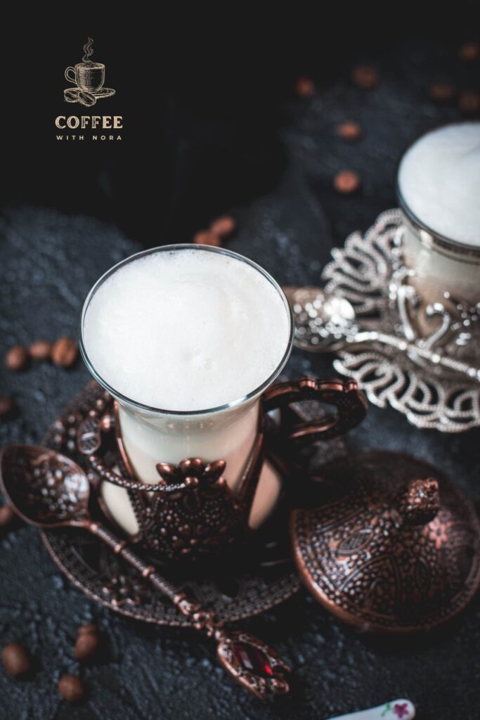 Gorgeous medieval glasses filled with delicious Breve coffee, placed on dark ground next to coffee beans.