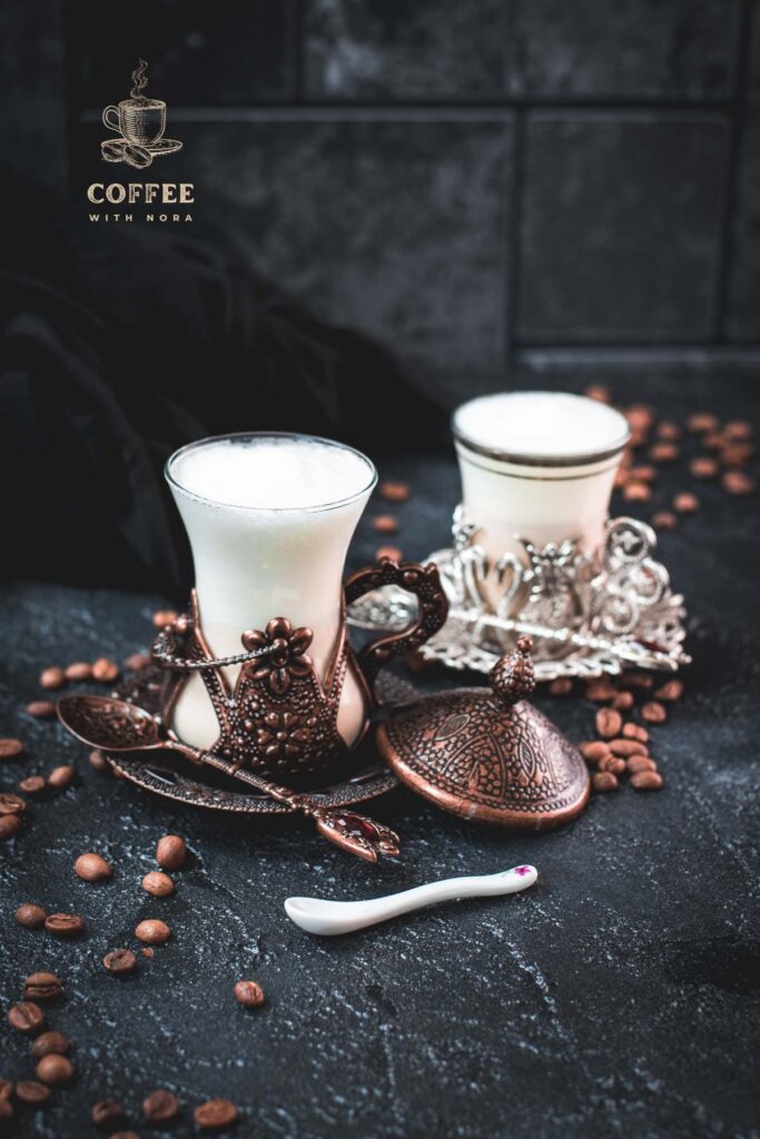 Gorgeous medieval glasses filled with delicious Breve coffee, placed on dark ground next to coffee beans.