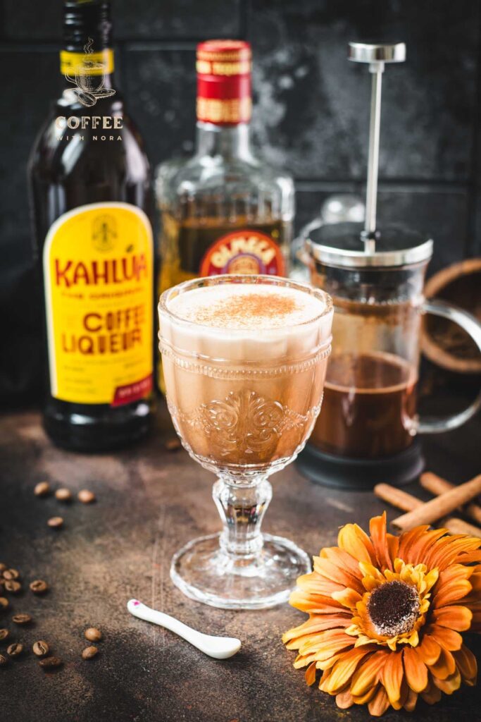 Rich French press Mexican coffee in gorgeous serving glass, placed on brown colored ground, next to orange-colored flower.