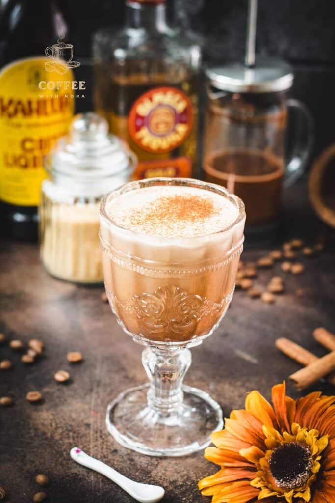 Rich French press Mexican coffee in gorgeous serving glass, placed on brown colored ground, next to orange-colored flower.