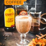 Rich French press Mexican coffee in gorgeous serving glass, placed on brown colored ground, next to orange-colored flower.