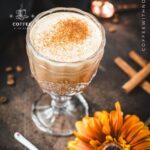 Rich French press Mexican coffee in gorgeous serving glass, placed on brown colored ground, next to orange-colored flower.