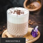 Gorgeous glass, filled with a delicious Mocha, topped with frothed milk, and garnished with chocolate sprinkles. Placed on a small wooden plate next to dark chocolate kisses.