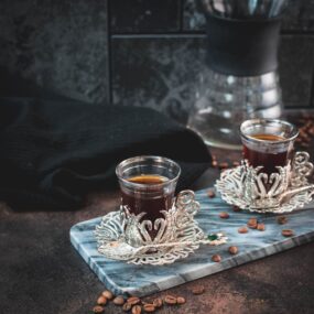 Gorgeous medieval glass filled with delicious specialty coffee placed on marbled plate.