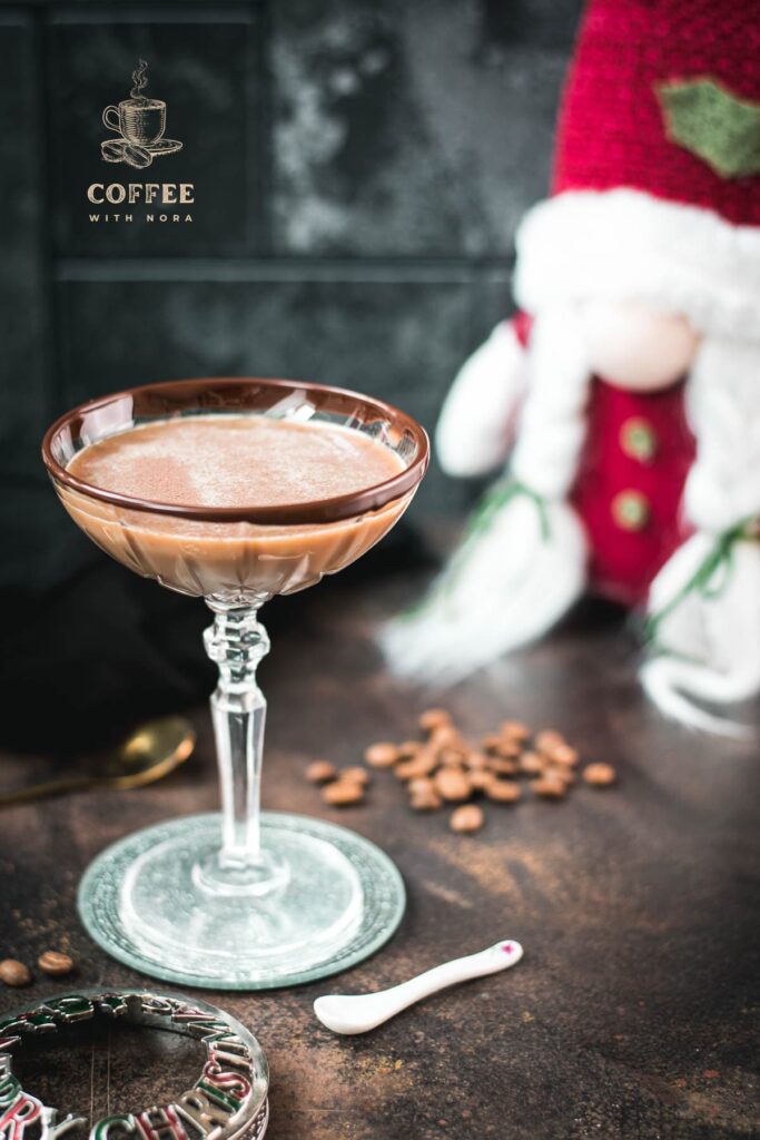 Creamy mocha martini in gorgeous glass, placed on glass coaster on dark ground.