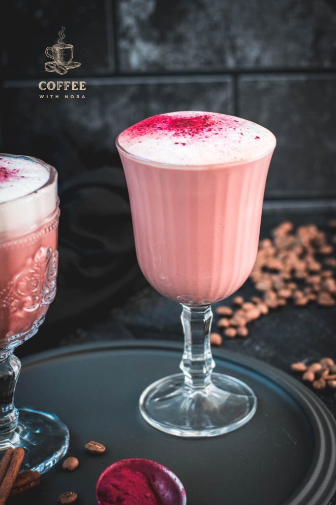 Delicious pink latte filled in gorgeous glasses placed on a dark plate.