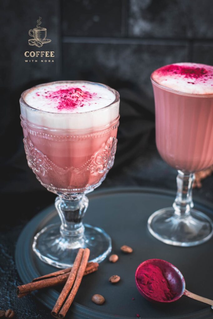 Delicious pink latte filled in gorgeous glasses placed on a dark plate.