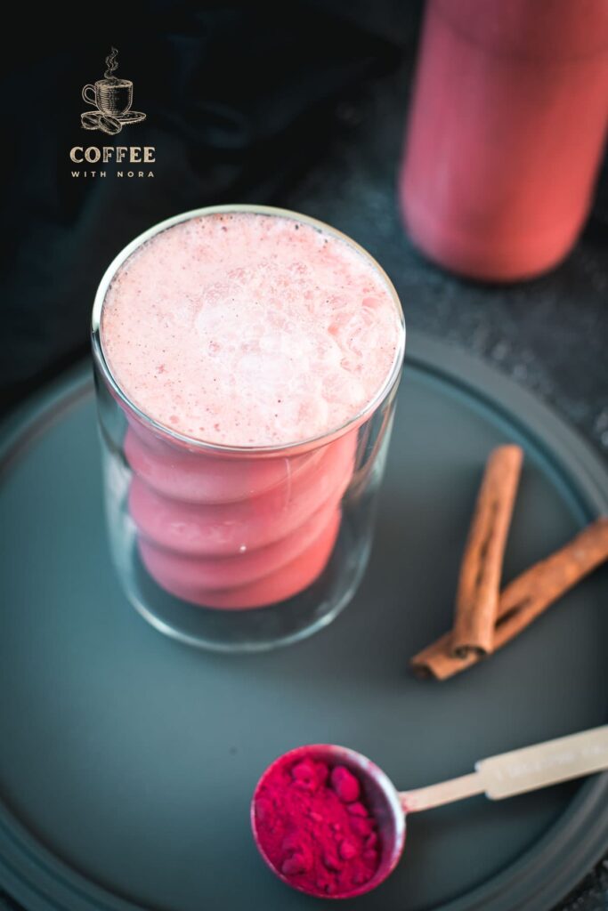 Delicious pink milk in gorgeous twisted glass placed on black plate.