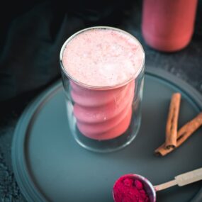 Delicious pink milk in gorgeous twisted glass placed on black plate.