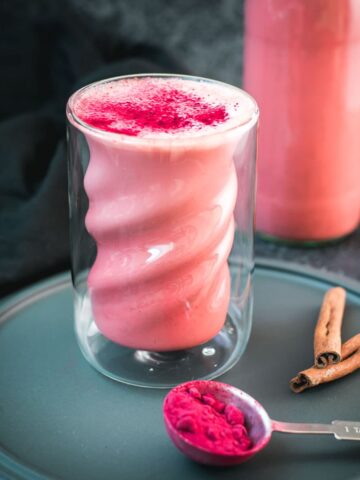 Delicious pink milk in gorgeous twisted glass placed on black plate.