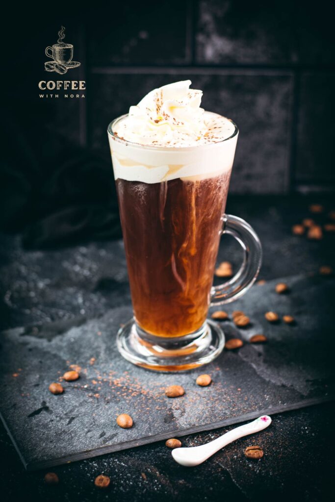 Delicious Irish coffee, topped with whipped cream and sprinkled with cocoa powder, placed on black slate plate.