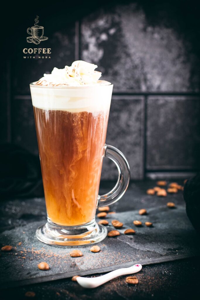 Delicious Irish coffee, topped with whipped cream and sprinkled with cocoa powder, placed on black slate plate.