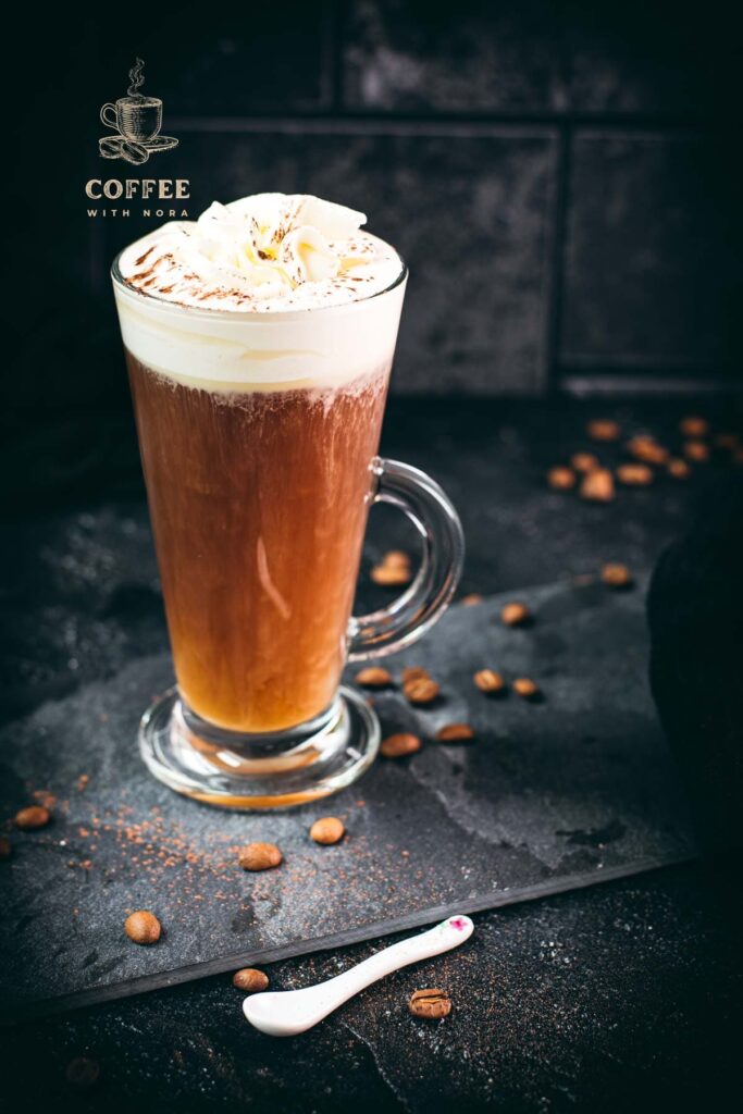 Delicious Irish coffee, topped with whipped cream and sprinkled with cocoa powder, placed on black slate plate.