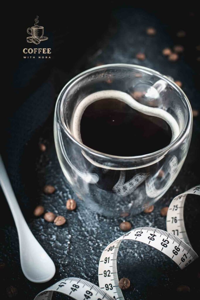 Heart-shaped coffee mug filled with black coffee, next to measuring tape on dark ground.