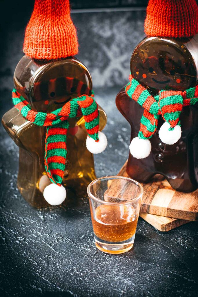 Easy homemade gingerbread simple syrup for coffees and cocktails in a small glass, placed next to two gingerbread man.