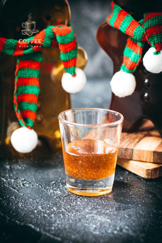 Easy homemade gingerbread simple syrup for coffees and cocktails in a small glass, placed next to two gingerbread man.