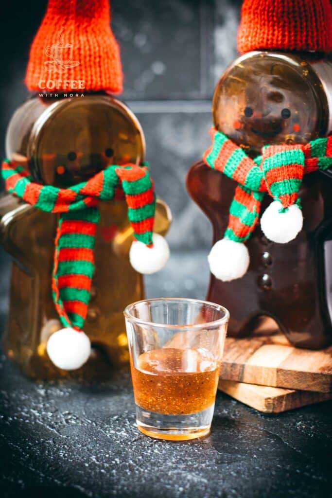 Easy homemade gingerbread simple syrup for coffees and cocktails in a small glass, placed next to two gingerbread man.