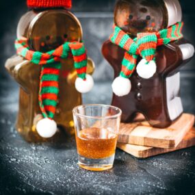 Easy homemade gingerbread simple syrup for coffees and cocktails in a small glass, placed next to two gingerbread man.